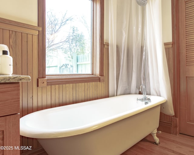 bathroom with wood-type flooring and a tub to relax in