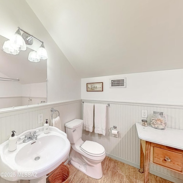 bathroom featuring lofted ceiling, toilet, sink, and hardwood / wood-style floors