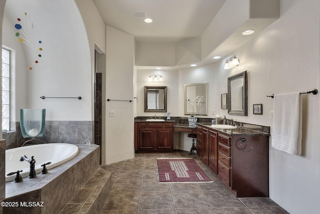 full bath with a sink, visible vents, two vanities, and a garden tub
