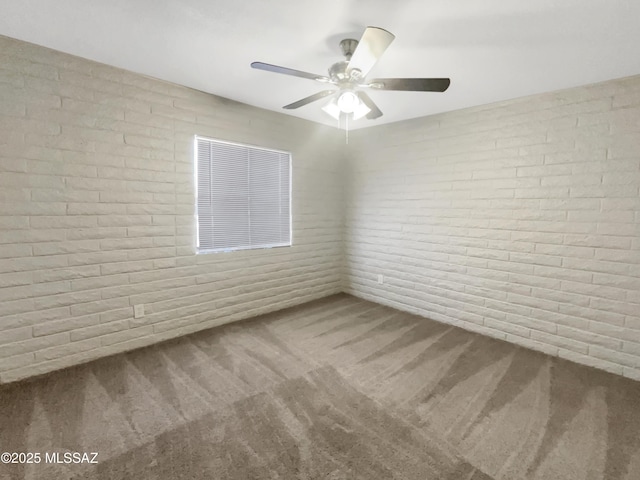 unfurnished room with ceiling fan, brick wall, and carpet floors