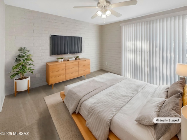 bedroom with light wood-type flooring, ceiling fan, and brick wall