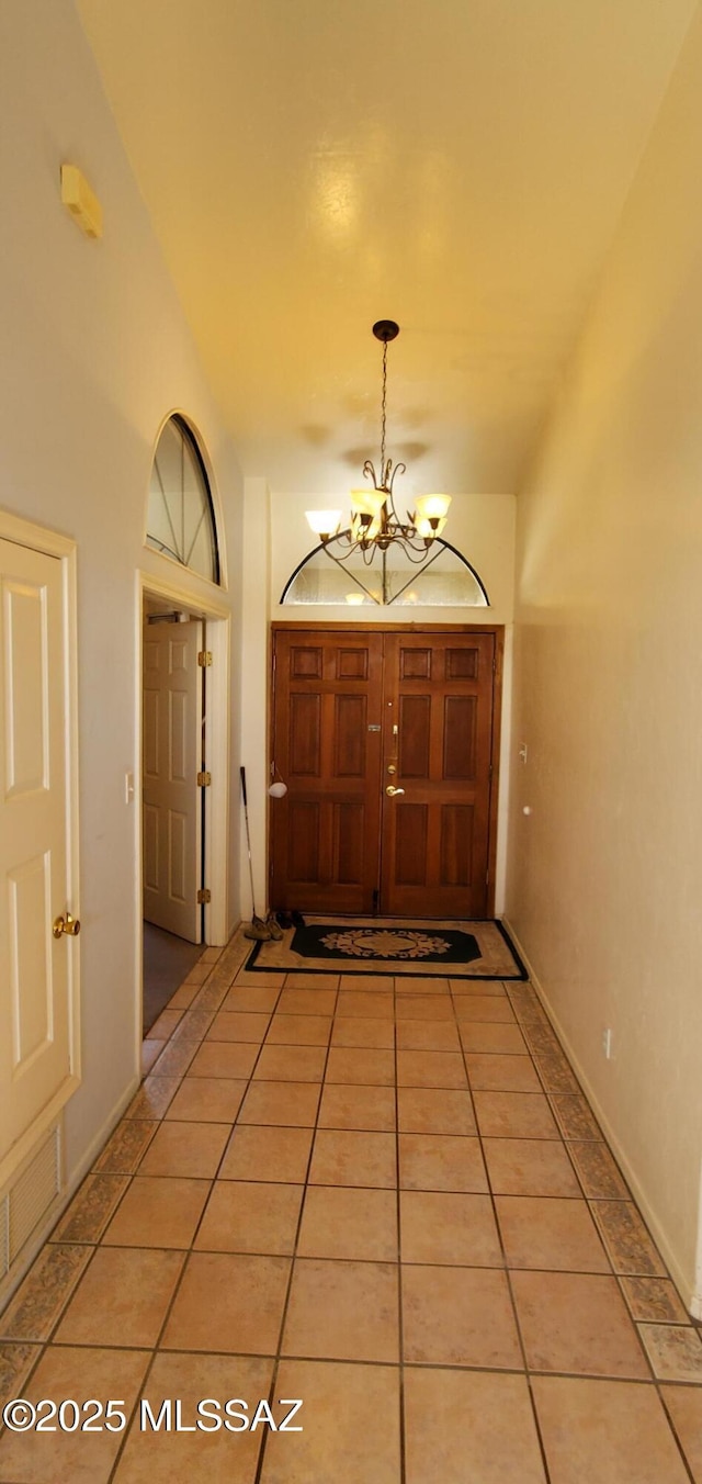 doorway featuring an inviting chandelier, vaulted ceiling, and light tile patterned floors