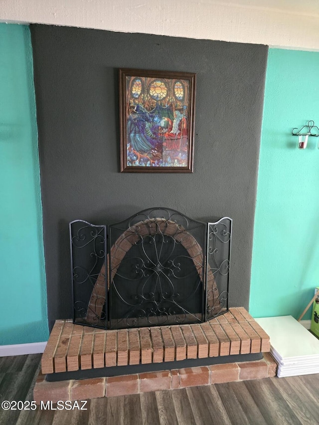 interior details with wood-type flooring and a brick fireplace