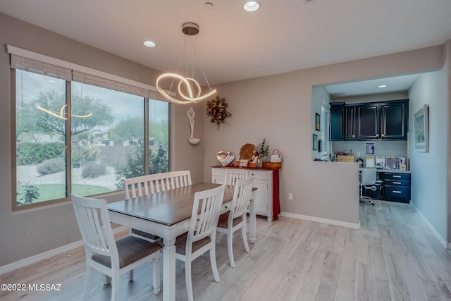 dining area with a chandelier, built in desk, and light hardwood / wood-style floors