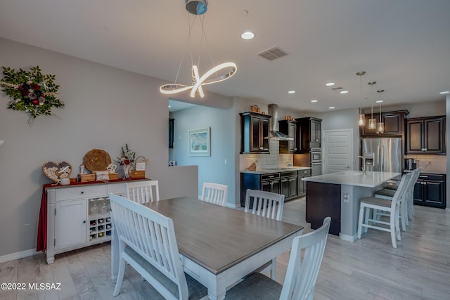 dining area featuring sink, a notable chandelier, and light hardwood / wood-style flooring