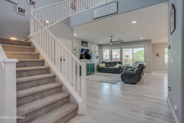 stairway with hardwood / wood-style floors and ceiling fan