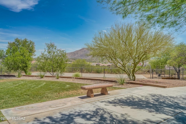 view of home's community featuring a mountain view, basketball hoop, and a lawn