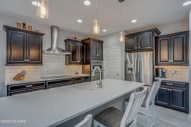 kitchen featuring pendant lighting, sink, decorative backsplash, stainless steel appliances, and wall chimney range hood