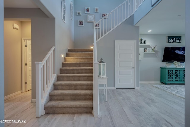 stairs with wood-type flooring and a towering ceiling