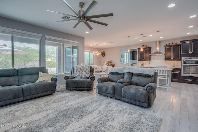 living room featuring ceiling fan, sink, and light hardwood / wood-style floors