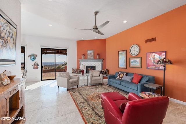 living room with a tile fireplace and ceiling fan