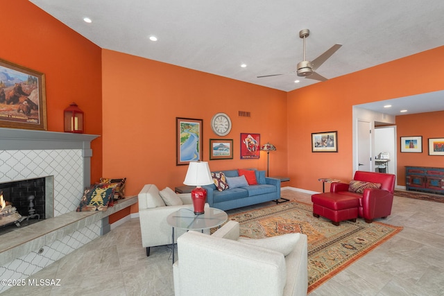 living room with a tiled fireplace and ceiling fan