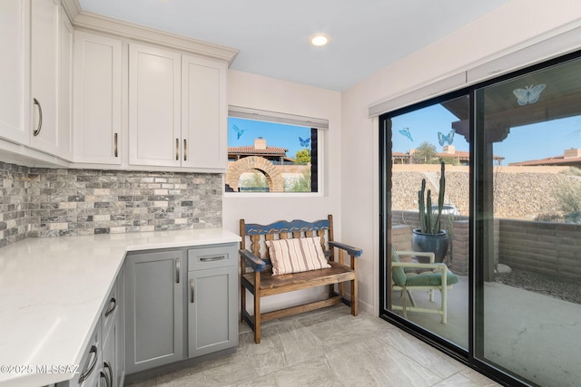 interior space featuring gray cabinets, light stone countertops, and decorative backsplash