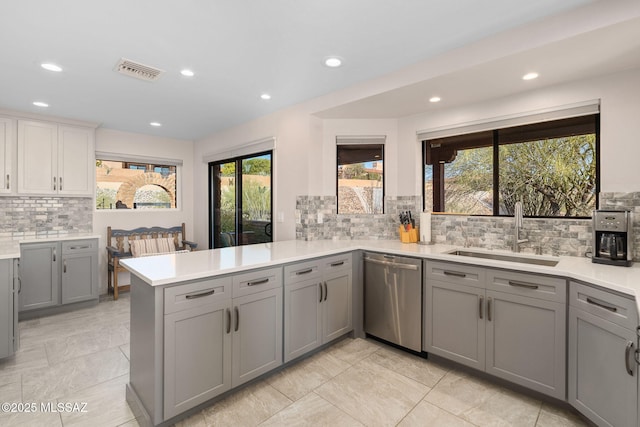 kitchen with sink, dishwasher, gray cabinetry, backsplash, and kitchen peninsula