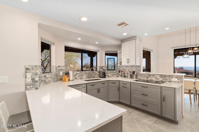 kitchen featuring sink, dishwasher, black electric stovetop, decorative light fixtures, and kitchen peninsula