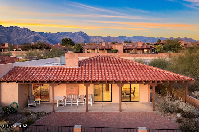 back house at dusk featuring a patio and a mountain view