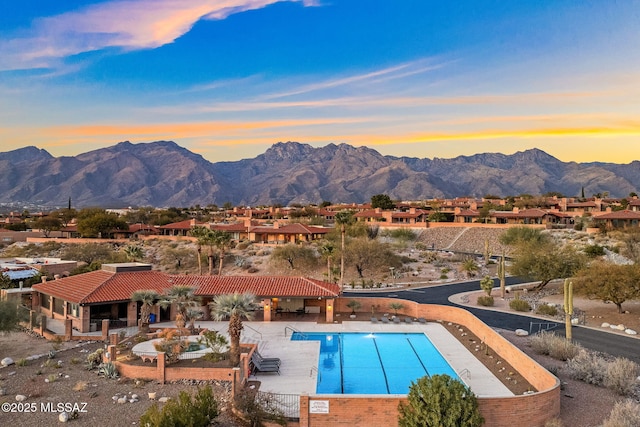 pool at dusk featuring a mountain view and a patio area