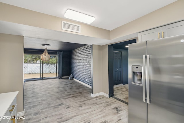 kitchen featuring white cabinetry, light countertops, stainless steel fridge with ice dispenser, light wood-style floors, and visible vents