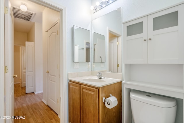 bathroom featuring vanity, wood-type flooring, and toilet