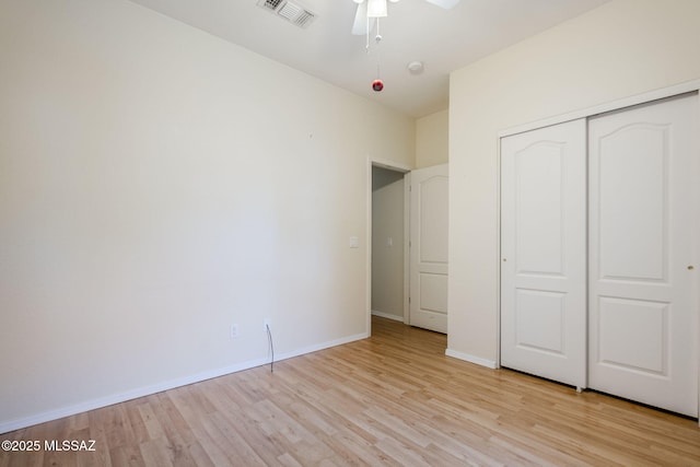 unfurnished bedroom featuring ceiling fan, a closet, and light wood-type flooring