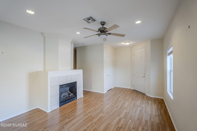 unfurnished living room with a tile fireplace, ceiling fan, and light hardwood / wood-style flooring