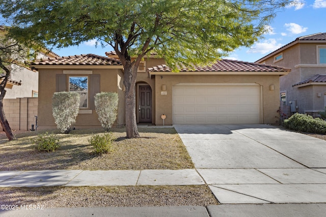 mediterranean / spanish home featuring driveway, an attached garage, a tile roof, and stucco siding