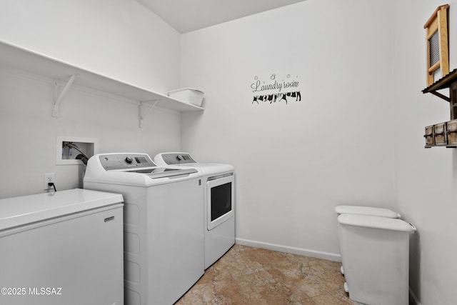 laundry area with washing machine and dryer, laundry area, stone finish floor, and baseboards