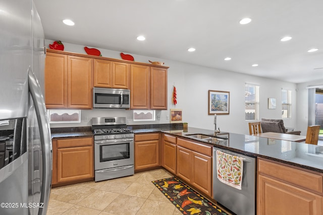 kitchen featuring appliances with stainless steel finishes, dark stone counters, a sink, and recessed lighting