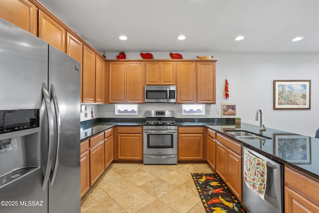 kitchen featuring dark stone counters, brown cabinets, stainless steel appliances, a sink, and recessed lighting