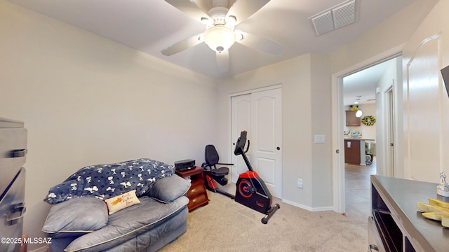 workout area with ceiling fan and light colored carpet