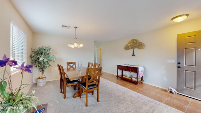 tiled dining area featuring an inviting chandelier