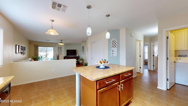 kitchen featuring light tile patterned flooring, a kitchen island, decorative light fixtures, washer / clothes dryer, and stainless steel dishwasher