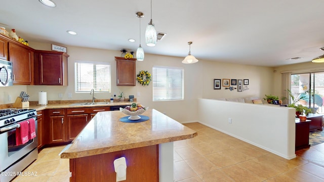 kitchen with appliances with stainless steel finishes, sink, hanging light fixtures, a center island, and light tile patterned floors