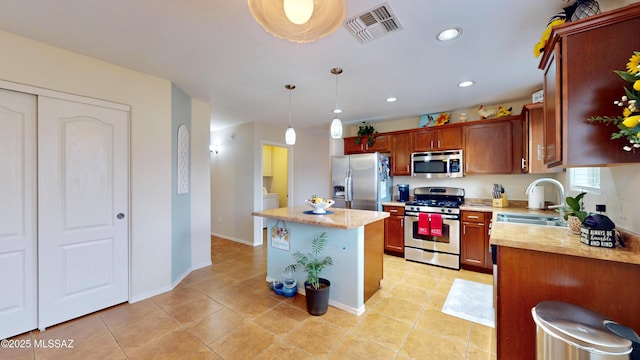 kitchen featuring a kitchen island, pendant lighting, sink, light tile patterned floors, and stainless steel appliances