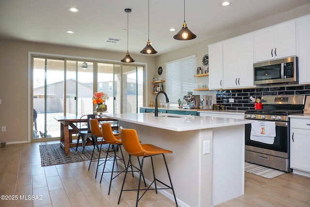 kitchen featuring white cabinetry, stainless steel appliances, sink, and a kitchen island with sink