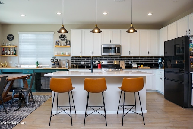 kitchen with appliances with stainless steel finishes, backsplash, hanging light fixtures, white cabinets, and a kitchen island