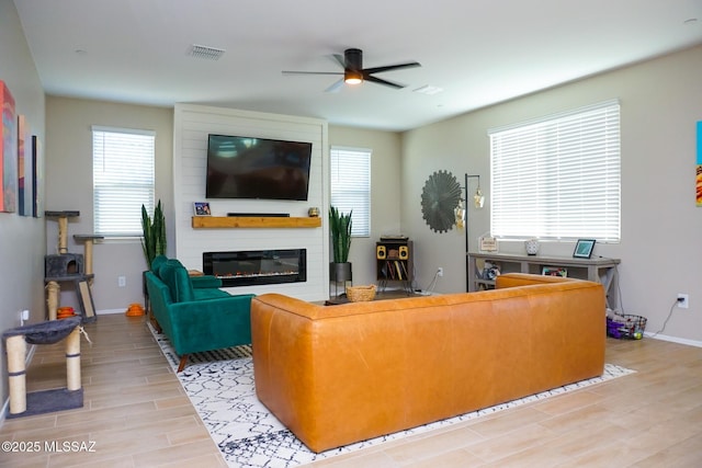 living room with ceiling fan, a fireplace, and light hardwood / wood-style floors