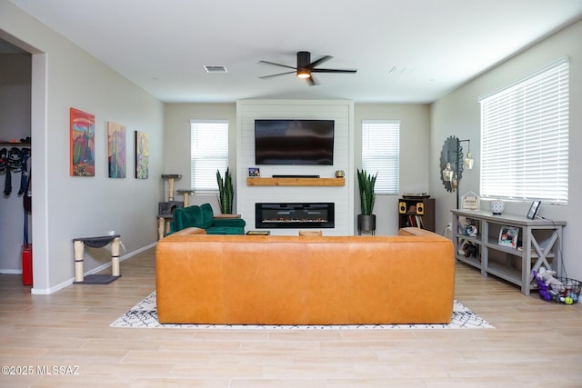 living room featuring a large fireplace, ceiling fan, and light hardwood / wood-style flooring