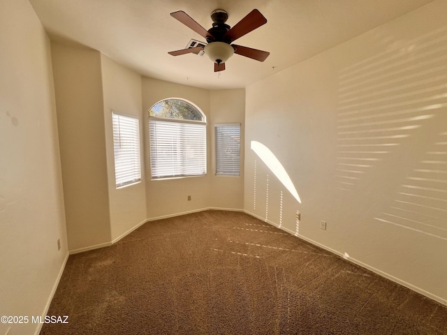 spare room featuring dark colored carpet and ceiling fan