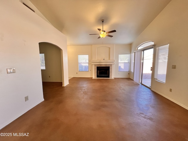 unfurnished living room featuring ceiling fan, a tiled fireplace, and vaulted ceiling