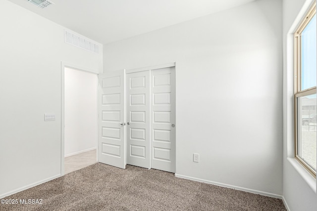 unfurnished bedroom featuring a closet, light carpet, and multiple windows