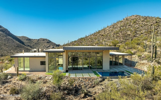 rear view of property with a patio area, a mountain view, and an outdoor pool