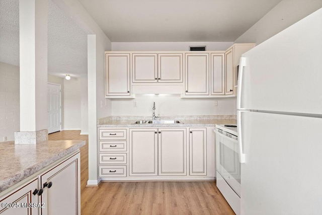 kitchen featuring sink, light stone counters, white appliances, light hardwood / wood-style floors, and cream cabinetry