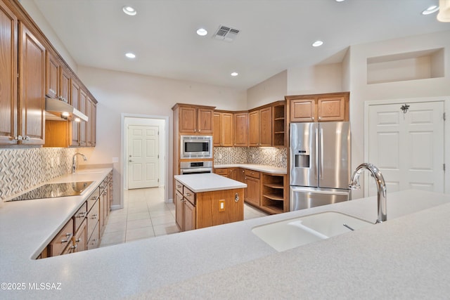 kitchen with a kitchen island, tasteful backsplash, sink, light tile patterned floors, and stainless steel appliances