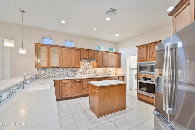 kitchen featuring decorative light fixtures, sink, backsplash, a center island, and stainless steel appliances