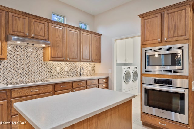 kitchen with sink, backsplash, stainless steel appliances, a kitchen island, and separate washer and dryer