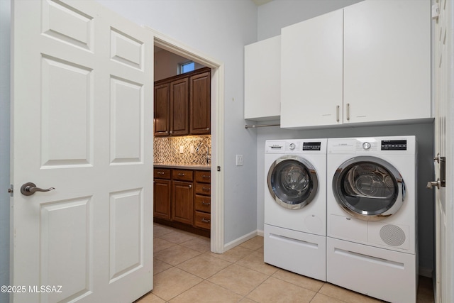 laundry area featuring cabinets, washing machine and clothes dryer, and light tile patterned floors