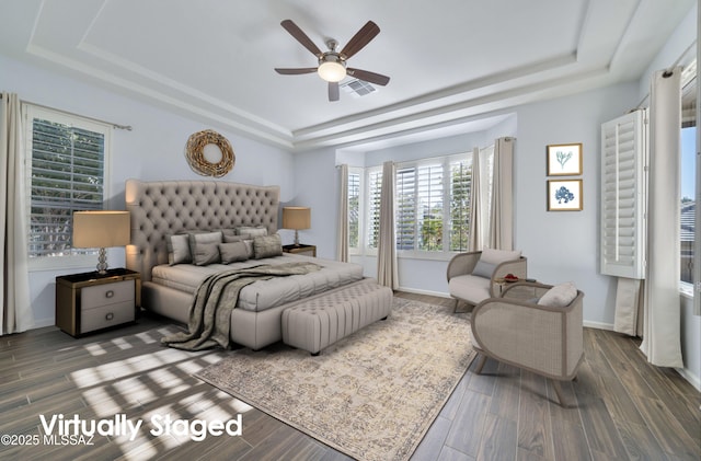 bedroom with dark wood-type flooring, ceiling fan, and a raised ceiling