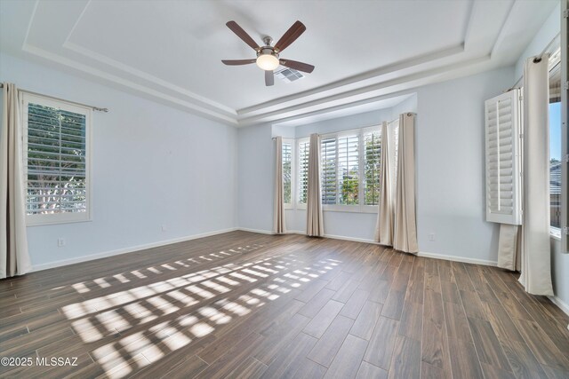 unfurnished room featuring dark hardwood / wood-style floors, ceiling fan, and a tray ceiling