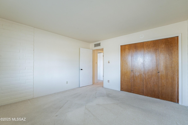 unfurnished bedroom with a closet, visible vents, and light carpet